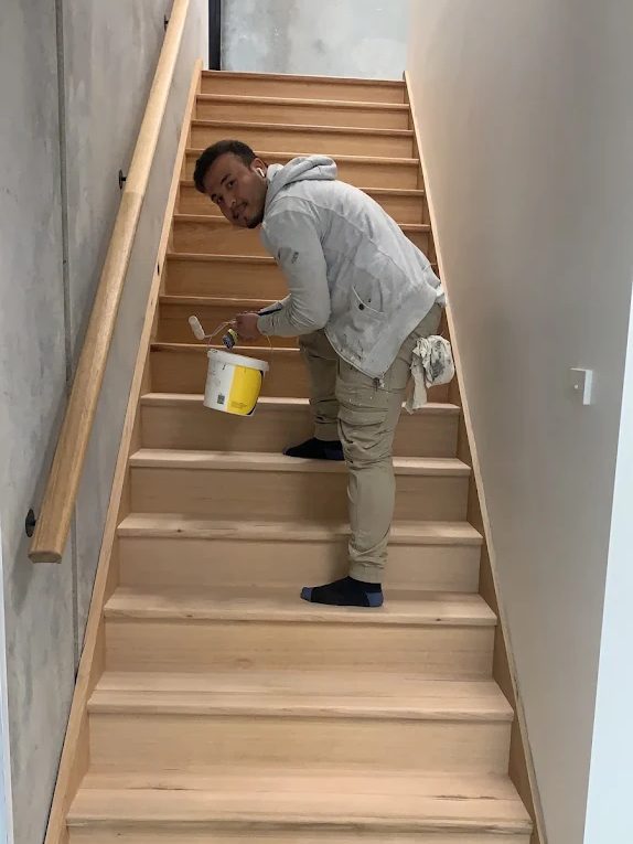 Hazara painter working on a staircase with a roller